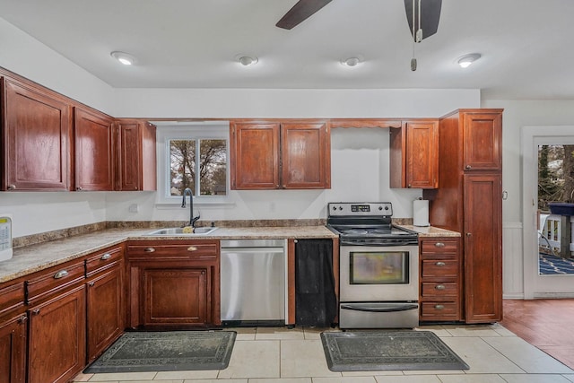 kitchen featuring a ceiling fan, a sink, light tile patterned floors, reddish brown cabinets, and appliances with stainless steel finishes