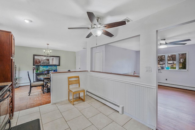 kitchen with a baseboard heating unit, electric range oven, wainscoting, and ceiling fan with notable chandelier
