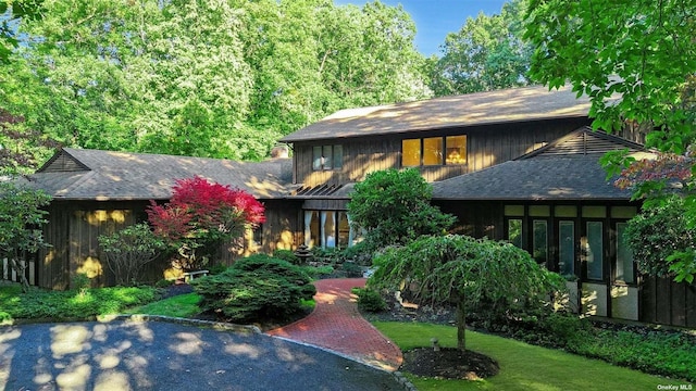 prairie-style house featuring roof with shingles and a front yard