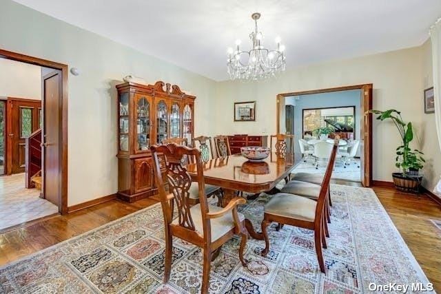 dining space with baseboards, an inviting chandelier, and wood finished floors