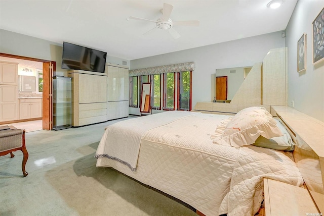bedroom featuring light colored carpet, connected bathroom, and ceiling fan