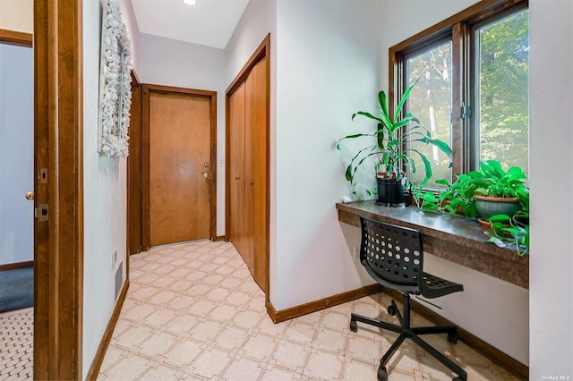 corridor featuring baseboards, visible vents, and light floors