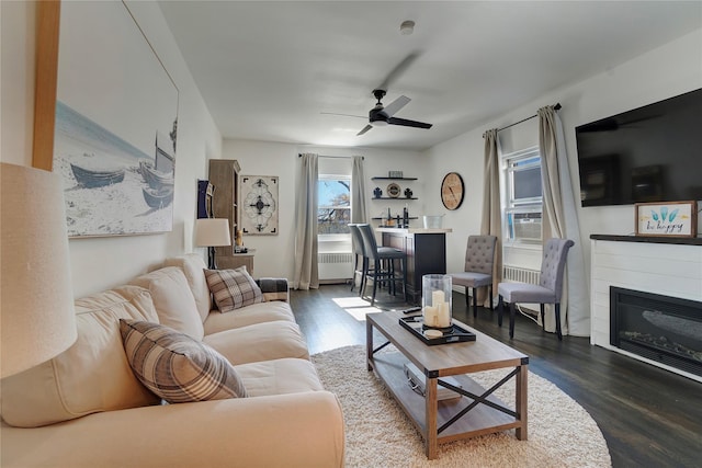 living area featuring bar area, wood finished floors, radiator heating unit, and ceiling fan