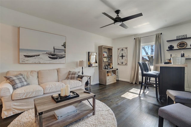 living room featuring baseboards, a ceiling fan, and dark wood finished floors