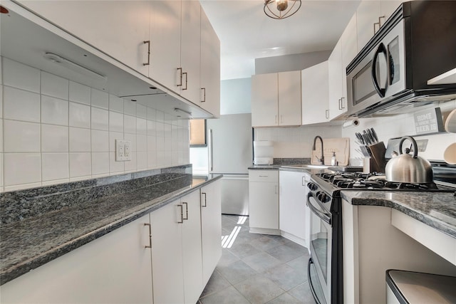 kitchen with tasteful backsplash, a sink, dark stone counters, and stainless steel appliances