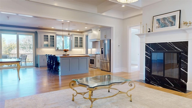 living area featuring baseboards, recessed lighting, beam ceiling, light wood finished floors, and a premium fireplace