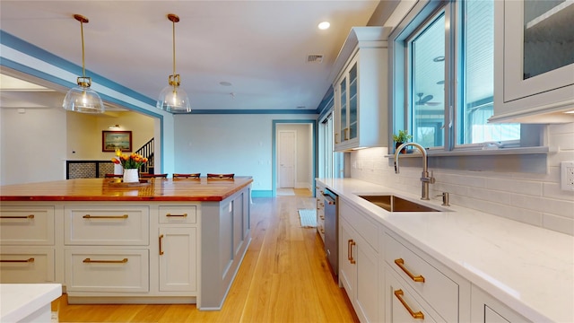 kitchen featuring butcher block countertops, backsplash, light wood finished floors, dishwasher, and a sink