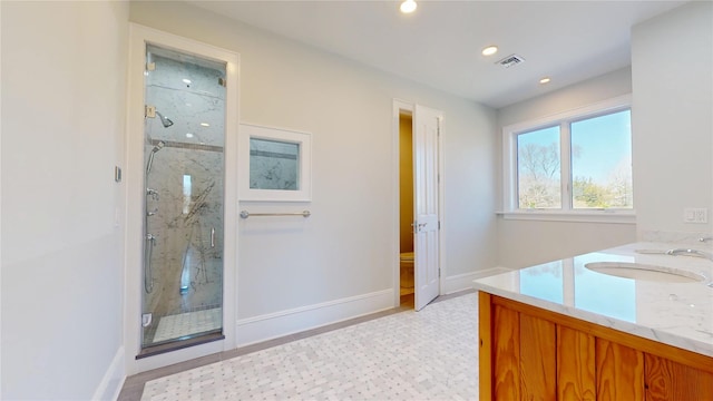 bathroom featuring visible vents, recessed lighting, a sink, a marble finish shower, and baseboards
