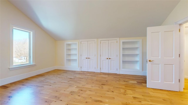 unfurnished bedroom featuring baseboards, light wood-style floors, and lofted ceiling