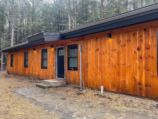 rear view of house with board and batten siding and a wooded view