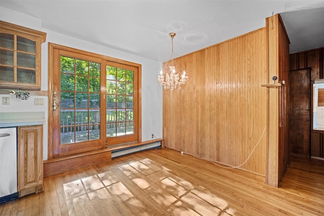 unfurnished dining area with a chandelier, a baseboard heating unit, and hardwood / wood-style floors