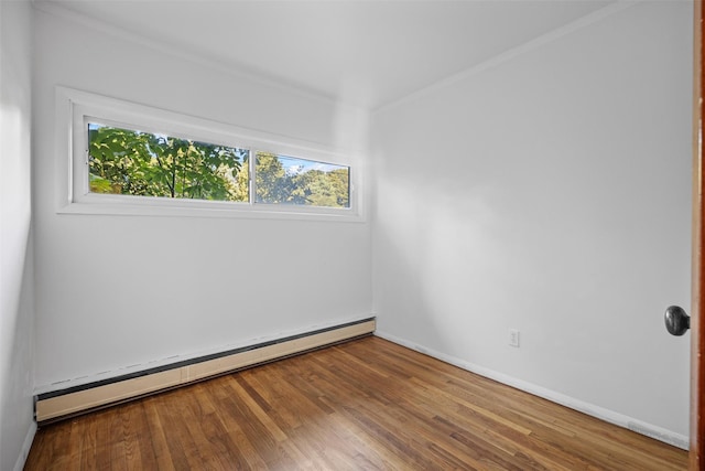 spare room with baseboard heating, baseboards, ornamental molding, and wood finished floors