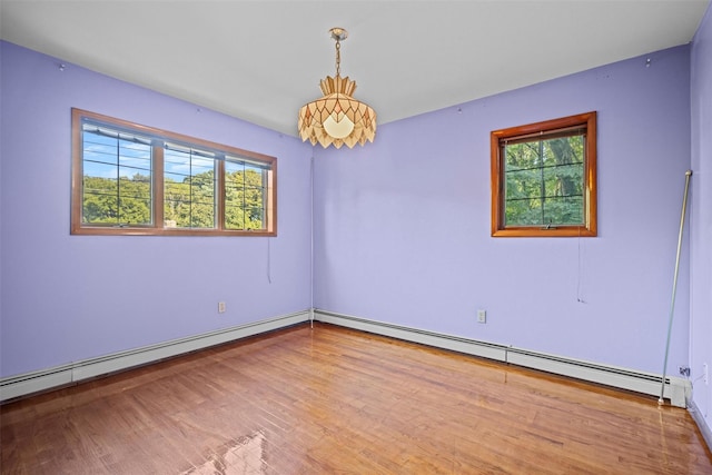spare room featuring baseboard heating, wood finished floors, and baseboards