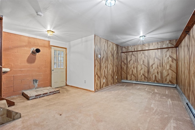 additional living space with carpet floors, a baseboard heating unit, wood walls, a baseboard radiator, and baseboards