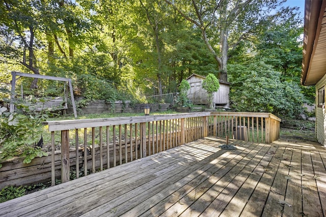 wooden deck featuring an outbuilding, fence, and a storage unit