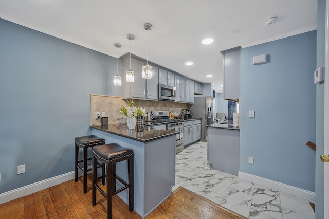 kitchen featuring a peninsula, recessed lighting, stainless steel appliances, decorative backsplash, and baseboards