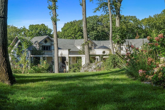 exterior space featuring a front lawn, stucco siding, and a balcony