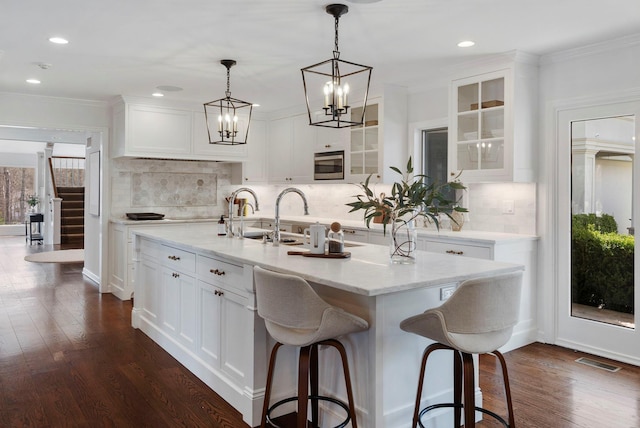 kitchen featuring dark wood-style floors, white cabinets, visible vents, and stainless steel microwave