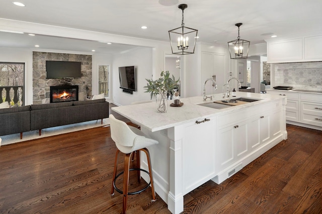 kitchen featuring white cabinetry, light stone counters, crown molding, and a sink