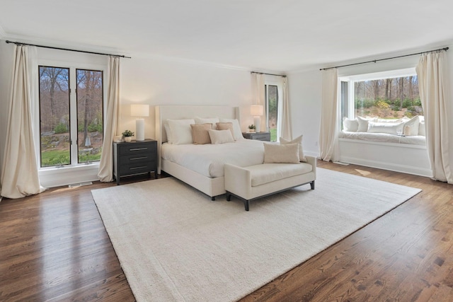 bedroom featuring multiple windows, wood finished floors, and ornamental molding