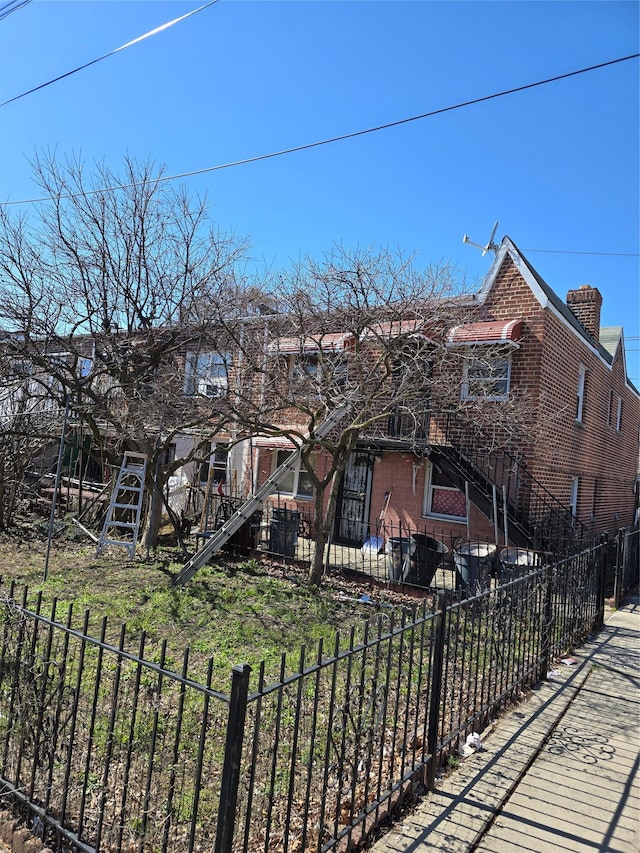 2866 Philip Ave, Bronx, NY 10465 - view of front of house featuring a fenced backyard, a chimney, brick siding, and stairs
