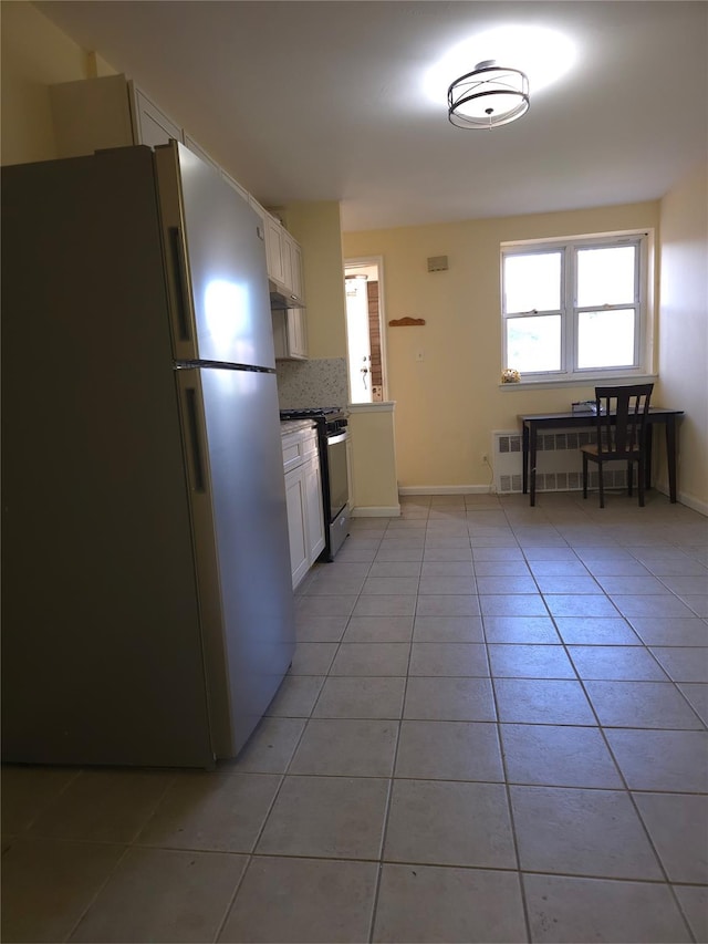 2864 Philip Ave, Bronx, NY 10465 - kitchen with freestanding refrigerator, range with gas cooktop, light tile patterned flooring, white cabinets, and backsplash