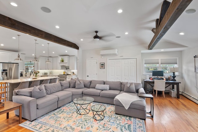 living room featuring beamed ceiling, a wall mounted air conditioner, ceiling fan, and light wood-type flooring