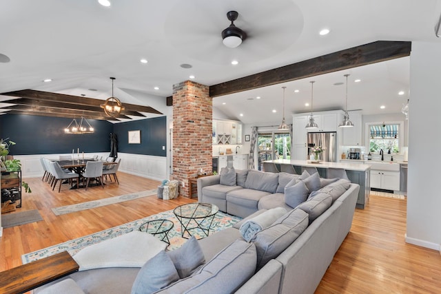 living room featuring lofted ceiling with beams, a wainscoted wall, light wood-style floors, and ornate columns