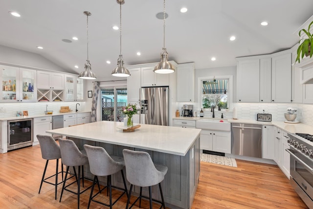 kitchen featuring a sink, plenty of natural light, decorative backsplash, appliances with stainless steel finishes, and wine cooler