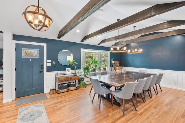 dining room featuring light wood-style flooring, a decorative wall, a wainscoted wall, and a notable chandelier