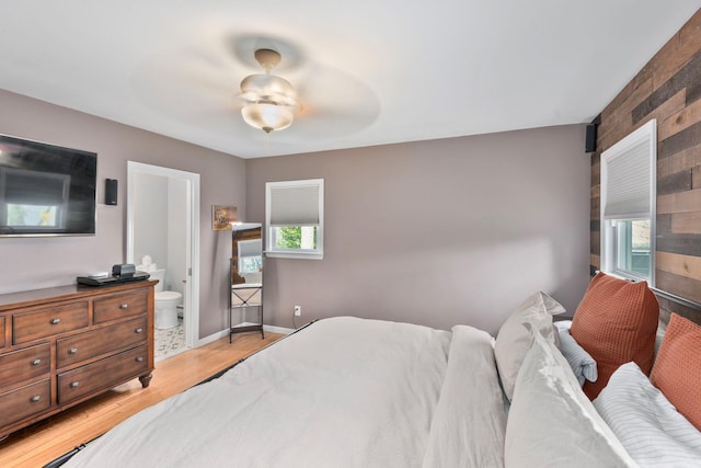 bedroom with light wood finished floors, baseboards, ceiling fan, and connected bathroom