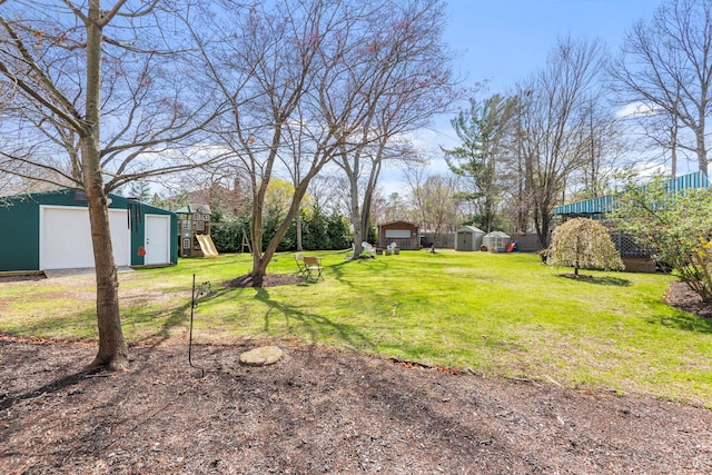 view of yard with a detached carport, an outdoor structure, a storage shed, and a playground