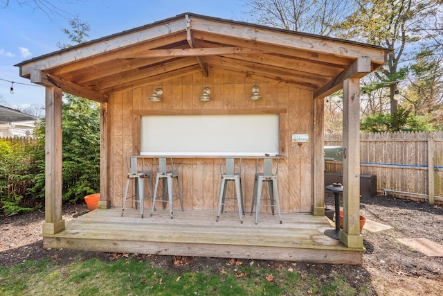 view of outdoor structure featuring outdoor dry bar and fence