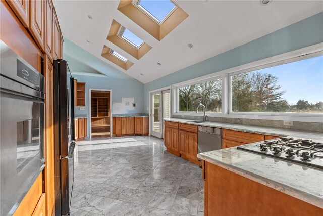 46 Mount Grey Rd, Setauket, NY 11733 - kitchen with a skylight, appliances with stainless steel finishes, light marble finish floors, brown cabinets, and light stone counters