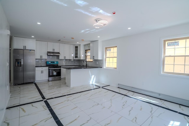 kitchen featuring glass insert cabinets, a peninsula, appliances with stainless steel finishes, under cabinet range hood, and dark countertops