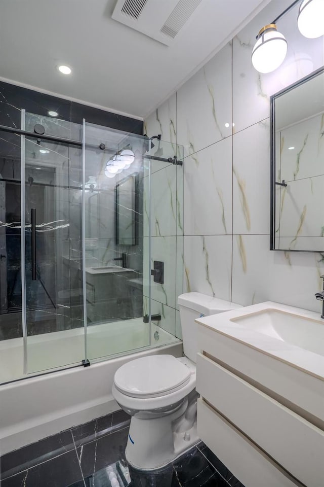 full bath featuring shower / bath combination with glass door, vanity, tile walls, toilet, and marble finish floor