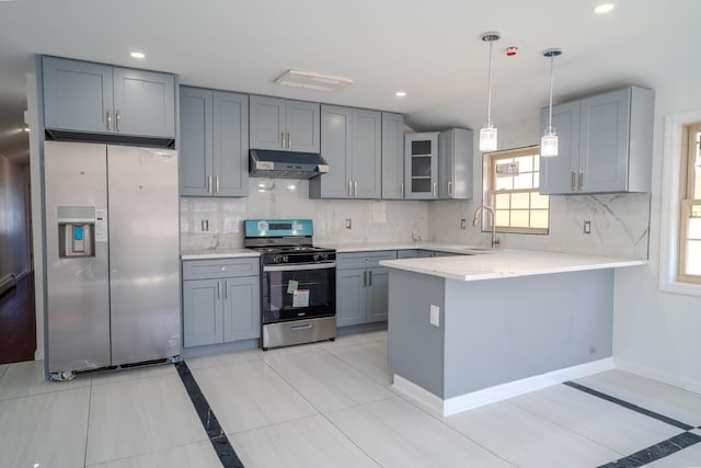 kitchen featuring gray cabinets, light countertops, under cabinet range hood, appliances with stainless steel finishes, and a sink