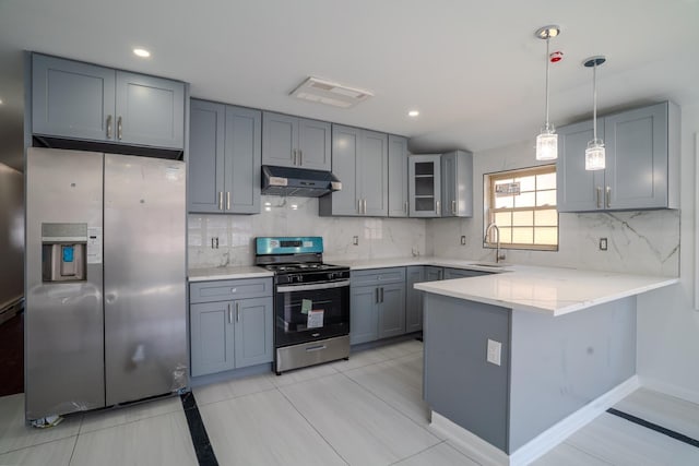 kitchen featuring a peninsula, under cabinet range hood, gray cabinetry, decorative backsplash, and stainless steel appliances