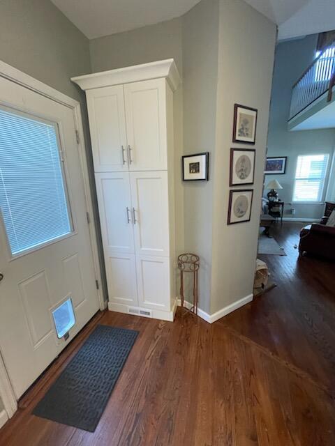 foyer with dark wood-type flooring and baseboards