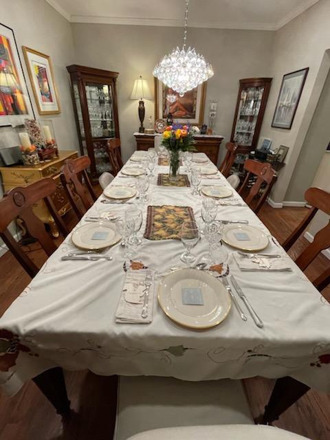 dining room featuring a notable chandelier, baseboards, crown molding, and wood finished floors
