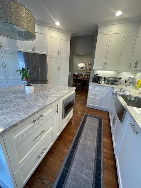 kitchen with stainless steel microwave, fridge, and white cabinets