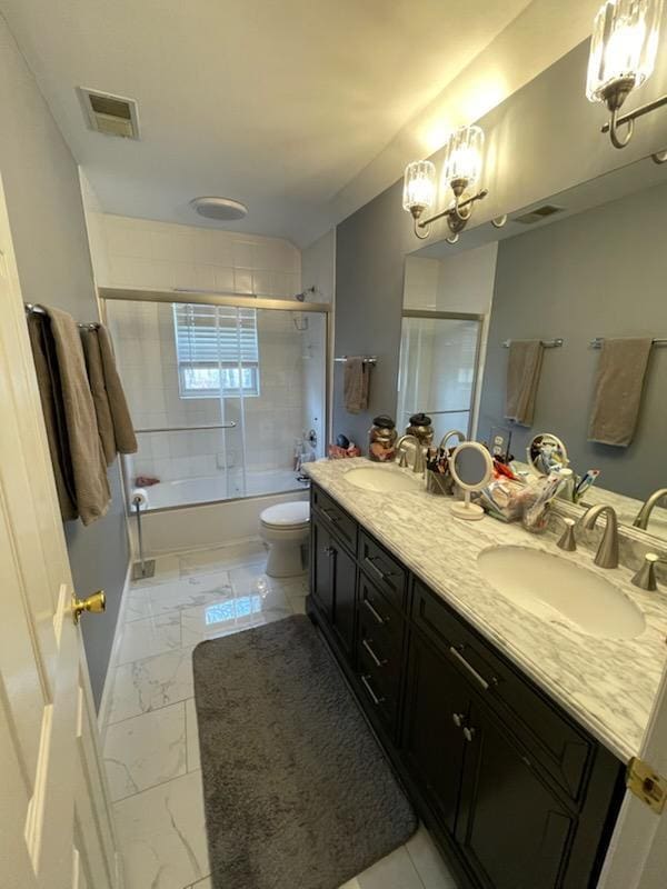 full bathroom featuring a sink, marble finish floor, visible vents, toilet, and shower / bath combination with glass door