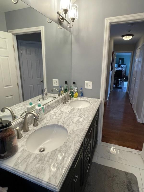 bathroom featuring a chandelier, double vanity, marble finish floor, and a sink