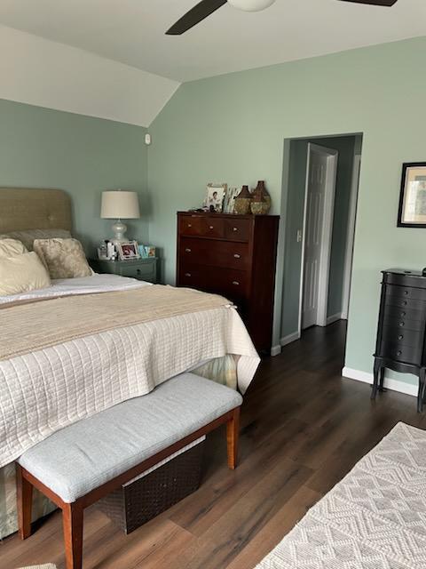 bedroom featuring dark wood-style flooring, baseboards, a ceiling fan, and lofted ceiling