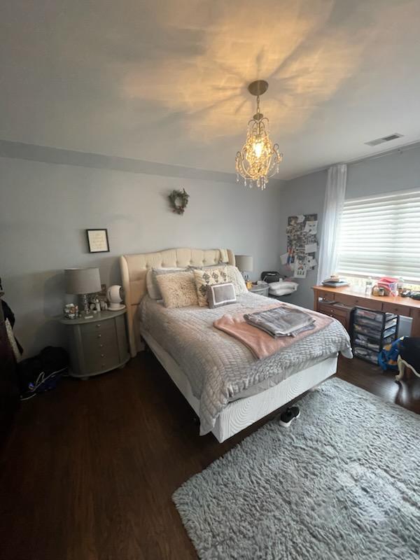 bedroom with visible vents, an inviting chandelier, and wood finished floors