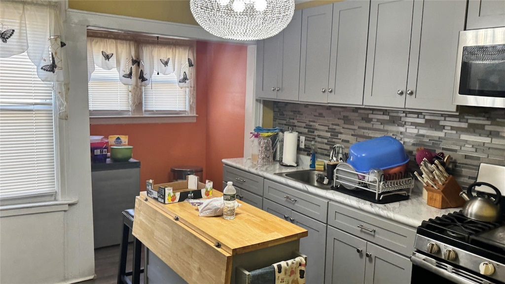 14539 115th Ave, South Ozone Park, NY 11436 - kitchen with gray cabinetry, a notable chandelier, appliances with stainless steel finishes, and tasteful backsplash