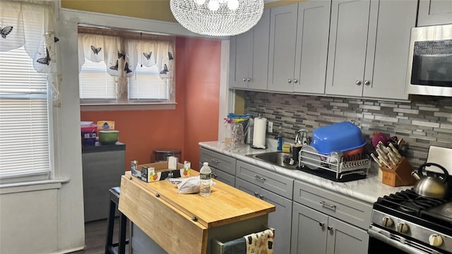 14539 115th Ave, South Ozone Park, NY 11436 - kitchen with gray cabinetry, a notable chandelier, appliances with stainless steel finishes, and tasteful backsplash