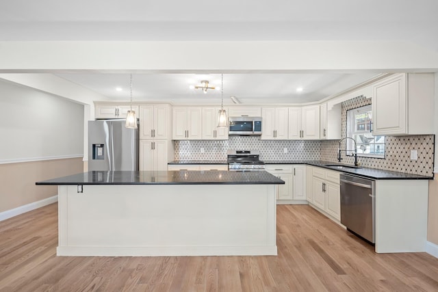 kitchen with a kitchen island, dark countertops, a sink, appliances with stainless steel finishes, and backsplash