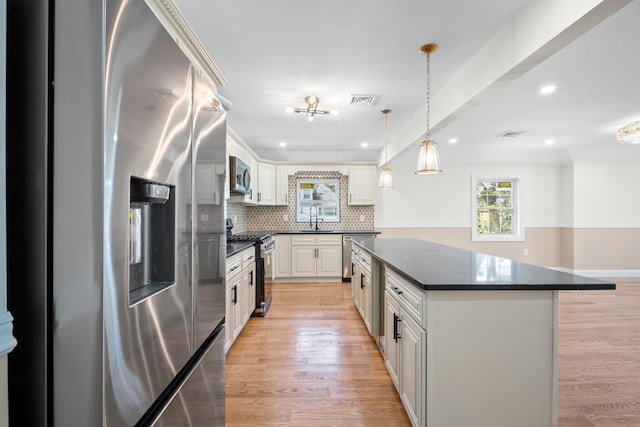 kitchen with visible vents, decorative backsplash, a center island, a sink, and appliances with stainless steel finishes