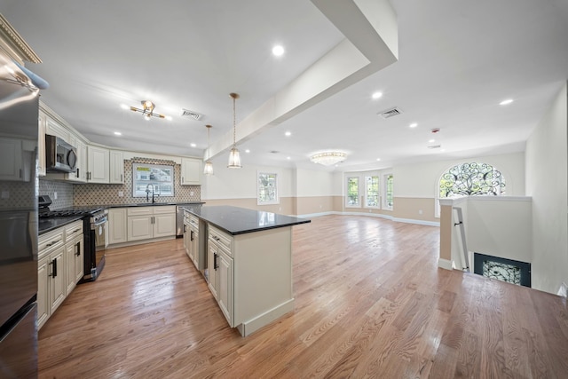 kitchen featuring visible vents, decorative backsplash, dark countertops, a center island, and appliances with stainless steel finishes